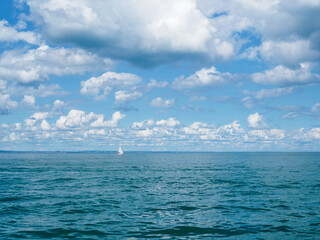 Obraz premium A floating, lonely, sailing yacht against the background of the sea and sky with clouds. Tor Bay – a bay in England, on the English Channel,La Manche Channel.