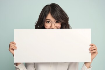 Fototapeta premium Cheerful young Asian woman standing behind blank white banner