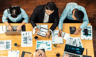 Panorama top view diverse group of business analyst team analyzing financial data report paper on meeting table. Chart and graph dashboard by business intelligence analysis. Meticulous