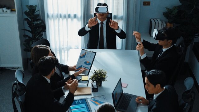 Top view of manager working on laptop and sending data analysis to business people by using VR glass headset while diverse team planning marketing strategy and looking at financial graph. Directorate.