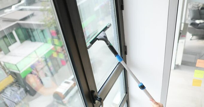 Washing a window with a scraper in a city apartment