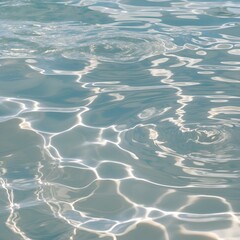 Fototapeta premium Close-up view of a water surface, showcasing a clear and rippling texture. The water appears to be shallow, with light reflections creating intricate patterns on the surface