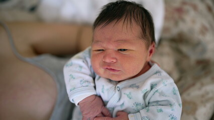 Close-up of a newborn baby transitioning from crying to calm while being held by mother. Intimate...
