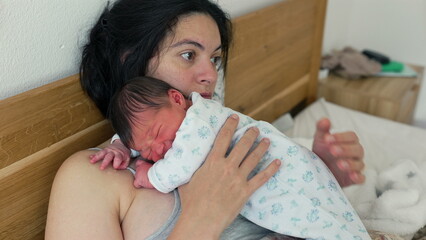 Exhausted mother resting with newborn on her chest, eyes closed, in a peaceful yet weary embrace,...