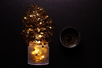 transparent jar with golden shiny shiny glitter on a black background