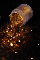 transparent jar with golden shiny shiny glitter on a black background