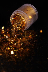transparent jar with golden shiny shiny glitter on a black background