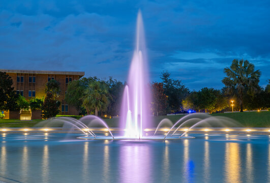 Fountain. Fountain in UCF University of Central Florida. Orlando FL. Fountain, colorful lights at night. Reflection in water. Professional long exposure photography. Tropical nature. Evening city park