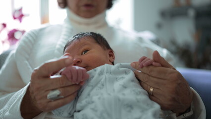 Obraz premium Grandmother tenderly gazing at her newborn grandchild, capturing a moment filled with love, care, and the special bond between the elder and the newest member of the family