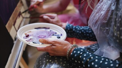 Process of drawing with brush, group class of talented students with painting easels and canvases during lesson of watercolour painting in auditorium, drawing class for adult artists in art school,