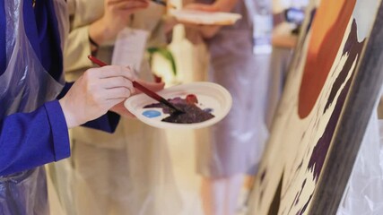 Process of drawing with brush, group class of talented students with painting easels and canvases during lesson of watercolour painting in auditorium, drawing class for adult artists in art school,