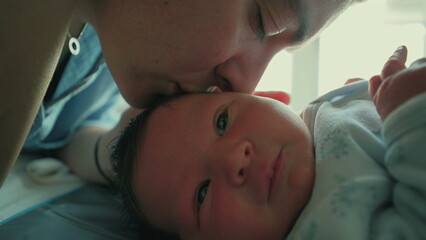 Intimate close-up of parent kissing baby's head, emphasizing loving bond during first moments of...