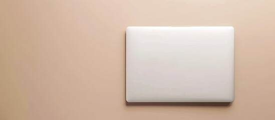 Top view of a closed white laptop on a beige backdrop. Copy space image. Place for adding text and design