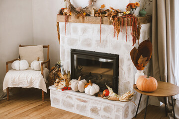 Stylish autumn decor of fireplace mantel in living room. Pumpkins, autumn leaves, nuts, candle on rustic wood on fireplace. Fall season decoration. Thanksgiving and Halloween