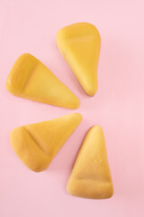 Slices of cheesecake covered with yellow chocolate velour on pink background with copy space. 