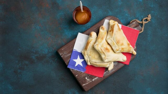 vista desde arriba de empanadas de pino junto a vaso de mote con huesillos, fondo celebraci&oacute;n fiestas patrias de Chile	