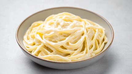 A serving of creamy alfredo pasta, isolated on a light grey background for a minimalistic, high-end restaurant feel