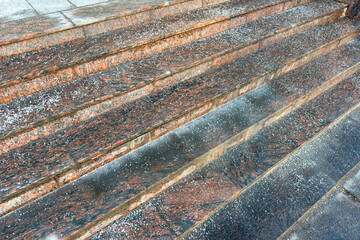 Deicing chemicals on stairs in winter. Salt grains on icy stone steps in cold season. Slippery surface sprinkled with technical salt and calcium, above view. Prevent slipping concept