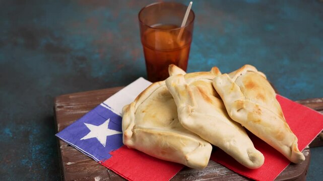 empanadas de pino junto a vaso de mote con huesillos, fondo celebraci&oacute;n fiestas patrias de Chile