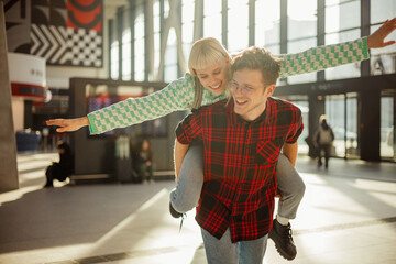 A young couple is having piggyback ride at train station.
