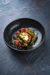 Traditional Turkish crispy sigara börek rolls stuffed with goat cheese in filo pastry and served with tomatoes and green asparagus as close-up in a Nordic design bowl