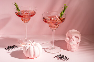 Halloween minimal concept with pink pumpkin, skull and cocktails. Creative holiday party background.