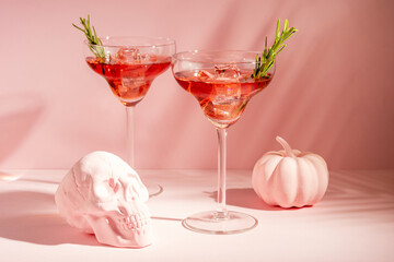 Halloween minimal concept with pink pumpkin, skull and cocktails. Creative holiday party background.