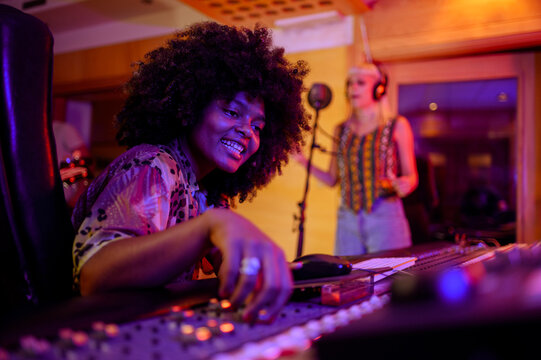 Hispanic woman sound engineer working at mixing panel in a music studio