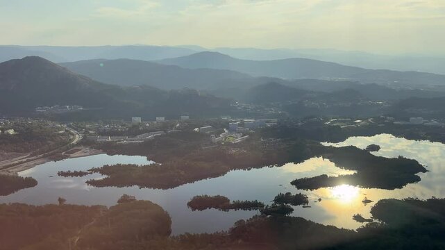 Side cockpit pilot captain view during landing approach roll from airport runway at Bergen Norway in summer with Fjords and sea lake boat and sun reflection