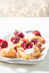 A tray of food with cranberries and cream on top