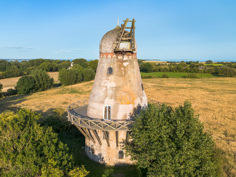 Aerial drone image of medieval derelict abandoned old wind mill, without windmill blades in rural agricultural field setting on danish island of Ly&oslash; in Baltic Sea