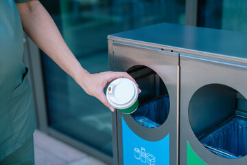 Close up of a female hand throwing empty paper cup to the waste bin