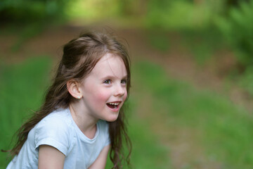 Fototapeta premium Little beautiful girl on the background of the road in the park. Happy childhood concept outdoors
