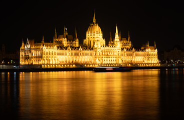 Fototapeta premium Budapest, Hungary. August 24, 2022. Amazing night shot of the parliament. The lighting enhances the beauty and elegance of the building. Three-quarter view from the Danube river side.