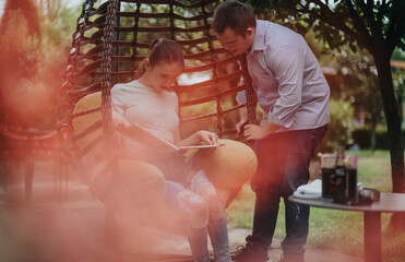 A boy with Down syndrome and a girl with a disability enjoy reading a book outdoors, surrounded by...