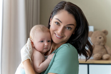 Beautiful nurse medical worker in gloves holding newborn baby in hands