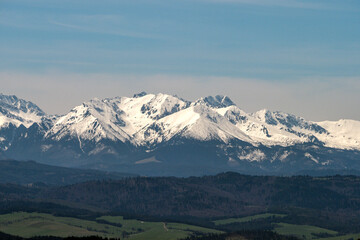 Ośnieżone szczyty górskie - góry Tatry. Widok z wieży widokowej na szczycie góry Koziarz w Beskidzkie Sądeckim. Panorama Tatr - zbliżenie