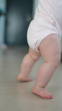 An adorable baby is happily taking their very first steps indoors, filled with joy and curiosity