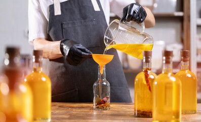 Craft sunflower oil with red pepper spices bottling in glasses bottle on manufacturing