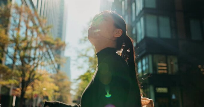 Asian, business woman and smile in city, walking for travel and lens flare with commute to work. Cityscape, metropolis or metro with professional in Tokyo, urban street and journey to workplace