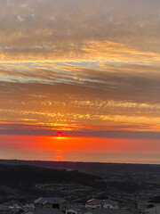 Bright orange and pink sunset overlooking city and sea with ocean views