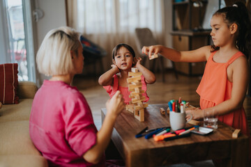 A mother engages with her young daughters in a fun and creative game at home, fostering family bonding and teamwork.