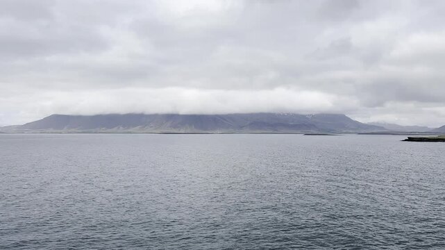 Reykjavik, Iceland - slowly cruising by Reykjav&iacute;kurborg coastline and cloud covered mountain Esjan enjoying stunning landscape view during sail away