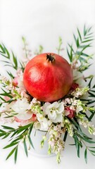 Red pomegranate and floral arrangement on white background