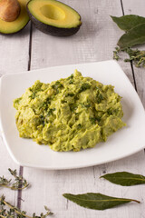 guacamole sauce with some avocados in the background and some spices