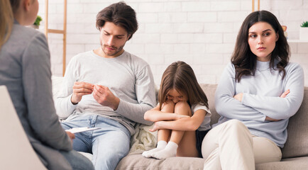 Family Counselling Concept. Unhappy Man And Woman And Their Upset Little Daughter Sitting At Psychologist's Office, Having Therapy