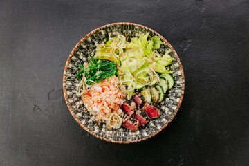 Healthy poke bowl with seared tuna, rice, seaweed salad, fresh vegetables - vibrant and nutritious