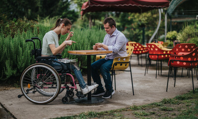A young boy with Down syndrome and a girl in a wheelchair play backgammon together at an outdoor...