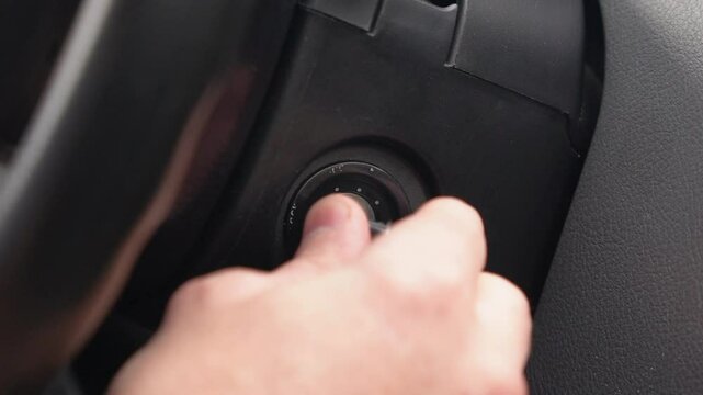 The driver inserts the key into the ignition of the car