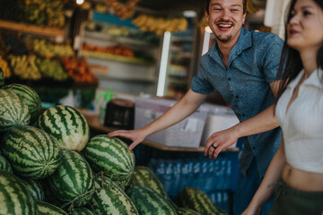 Two friends happily choosing fresh fruits and vegetables from a greengrocer. The vibrant market setting showcases an assortment of produce, creating a lively and cheerful atmosphere.